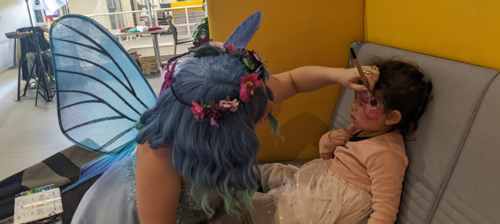 Alexis dressed as a fairy painting a child's face at an indoor party | Balloon Twister CT