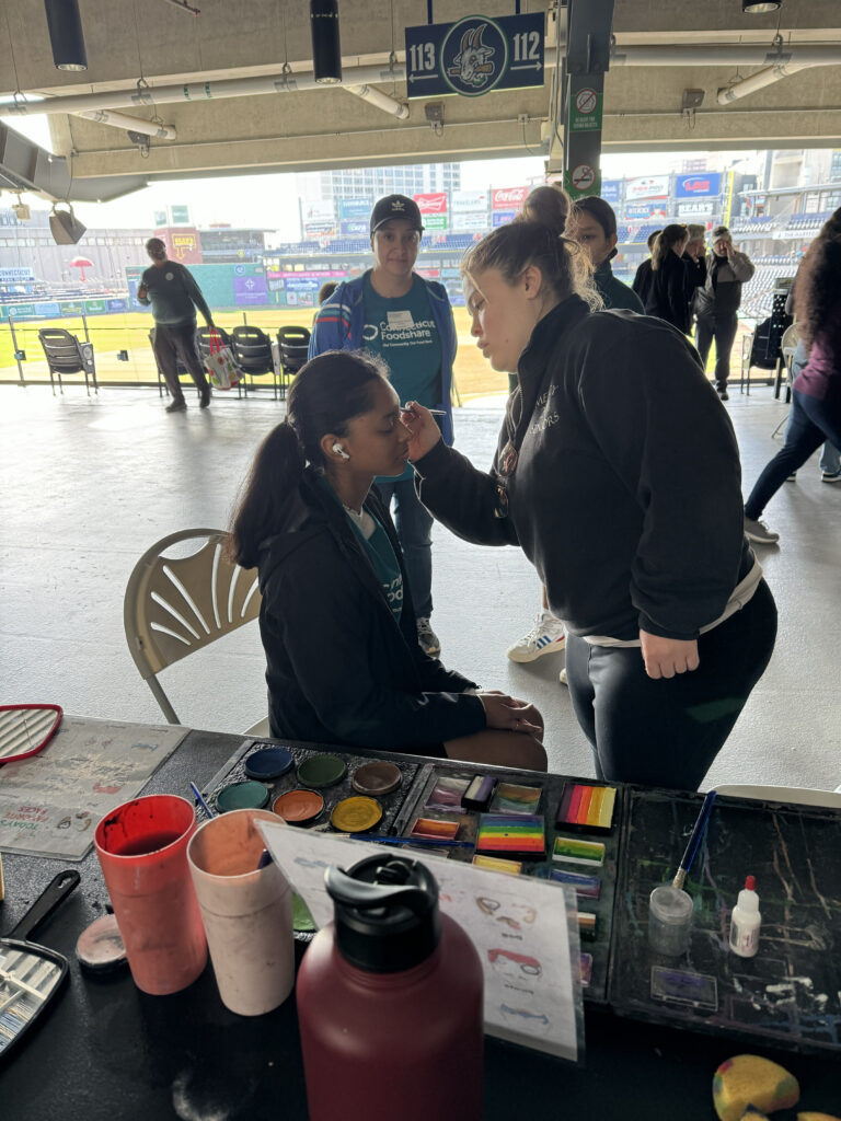 Alexis wearing all black face painting at a baseball stadium